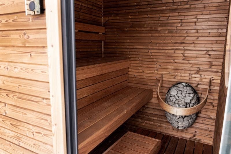 The cedar-lined interior of a home sauna with an electric stone heater